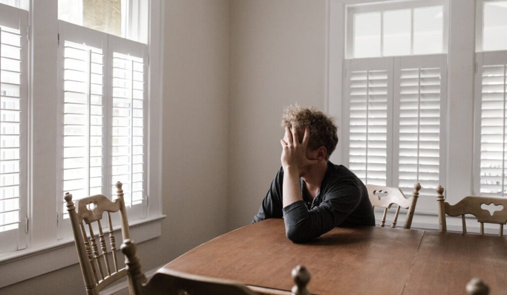 a person sitting at a table with his hands over his face