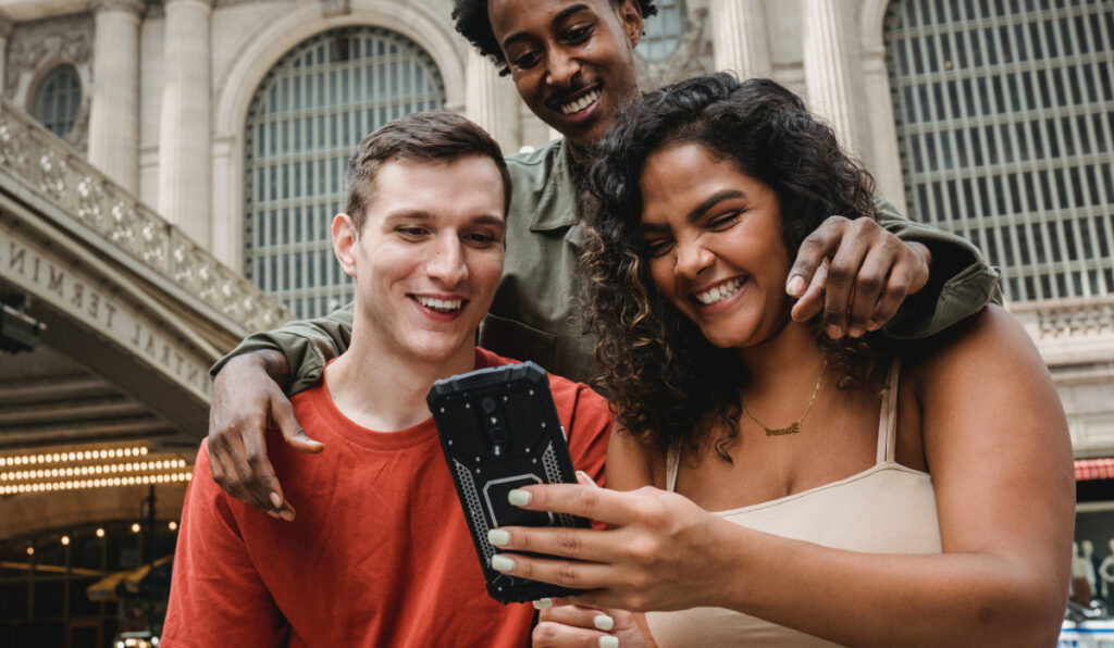 a group of people smiling and looking at a phone